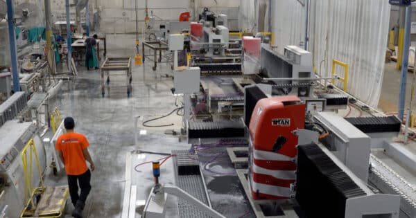 A man in an orange shirt and any pieces of Park Industries equipment in an industrial building